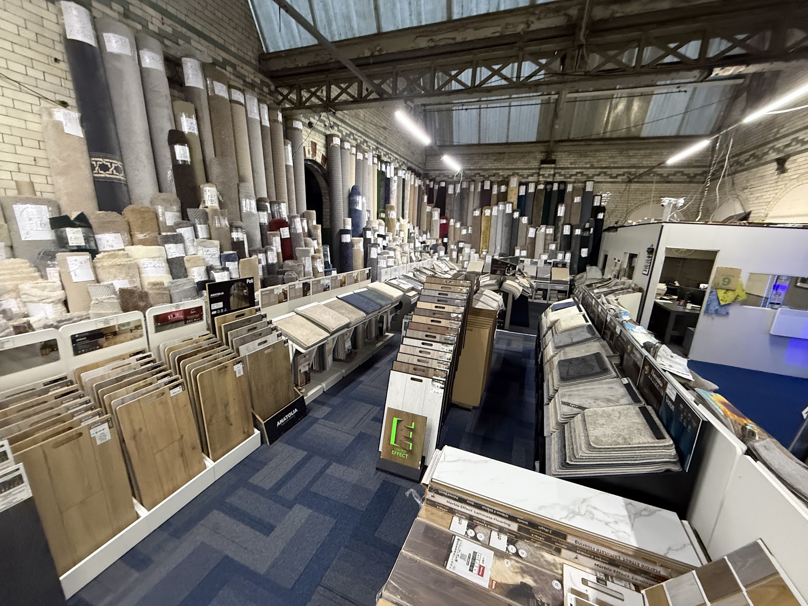 Wide view of the Lewis's Concept Carpets showroom floor, lined with laminate, LVT and carpet sample stands